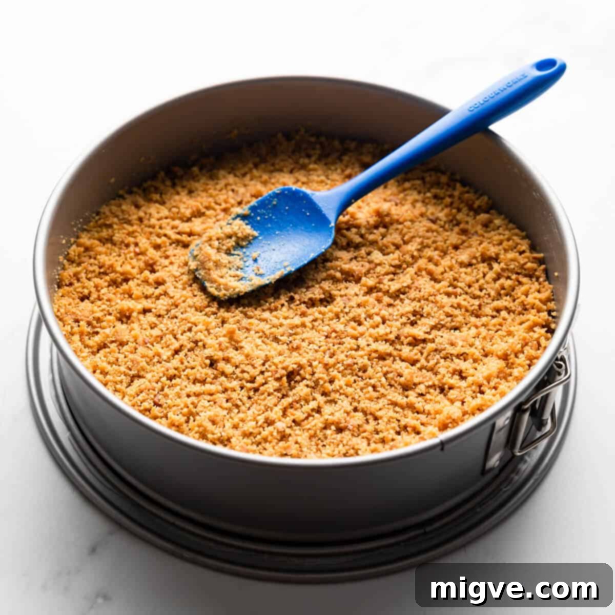 crushed biscuits crumbs with melted butter inside of the baking tin.