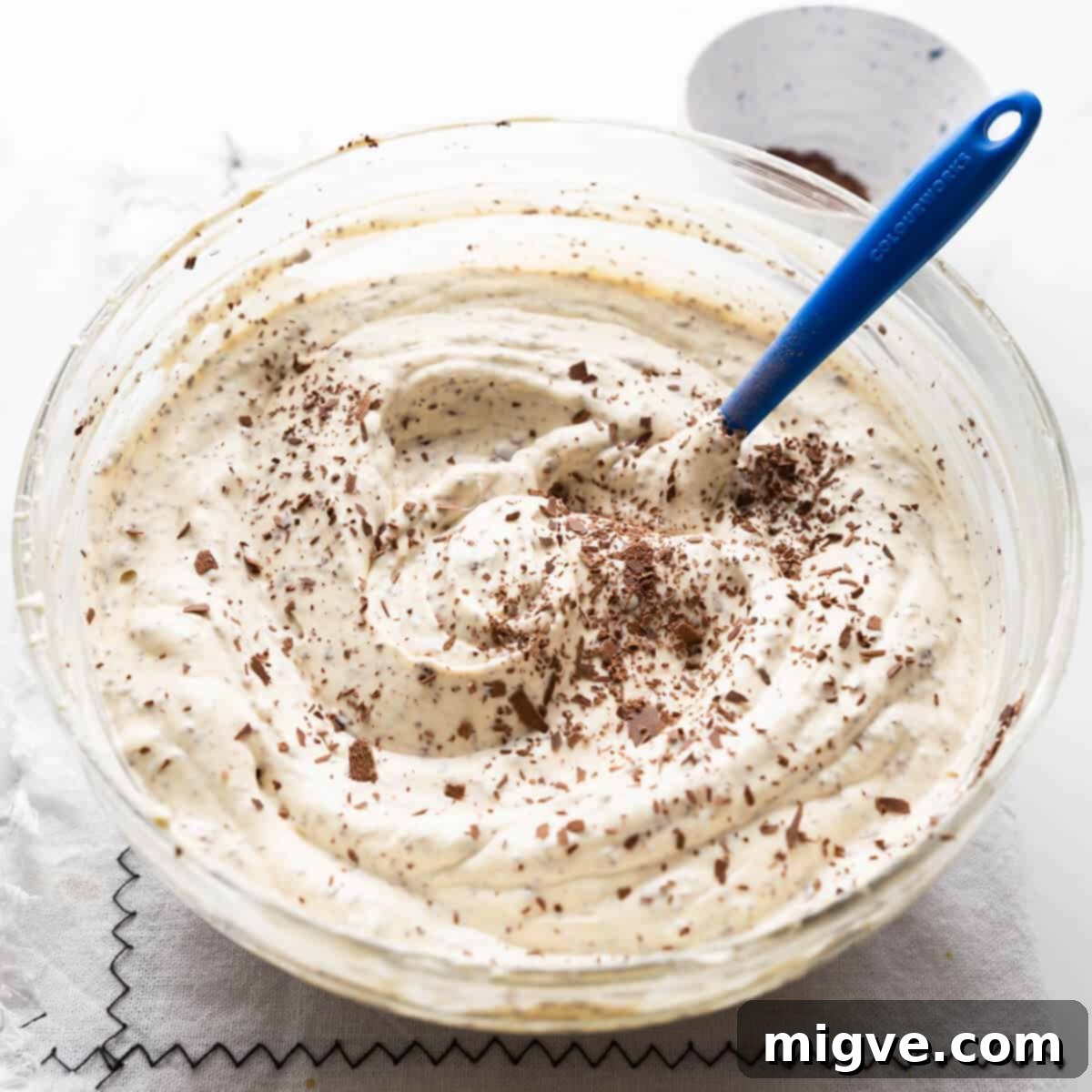 grated chocolate being mixed into the cheesecake filling.