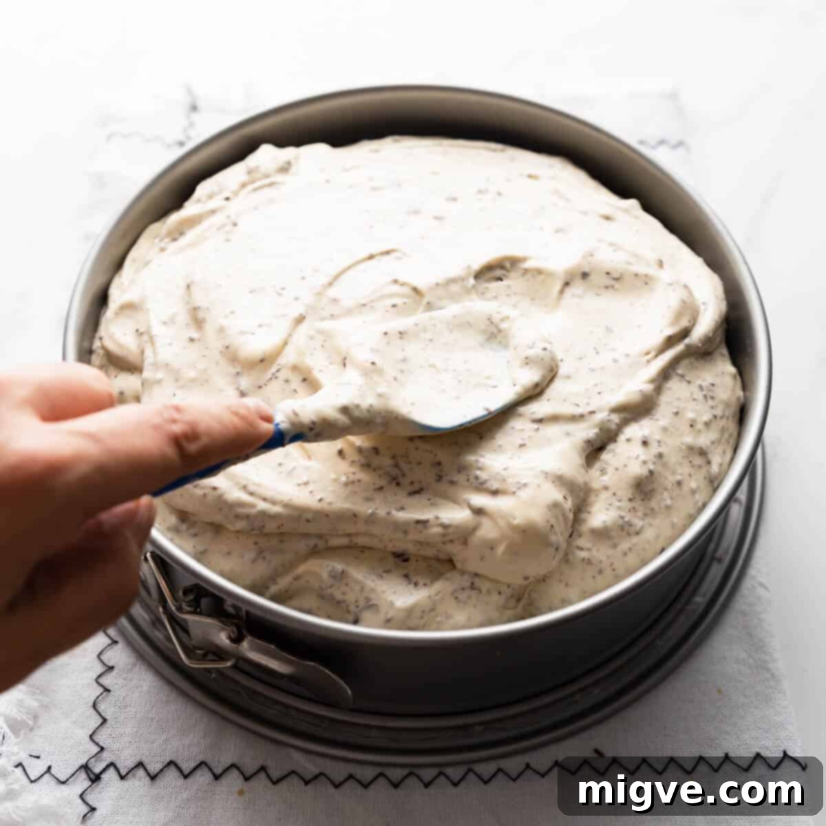baileys cheesecake filling being spread inside of the round baking tin with spatula.