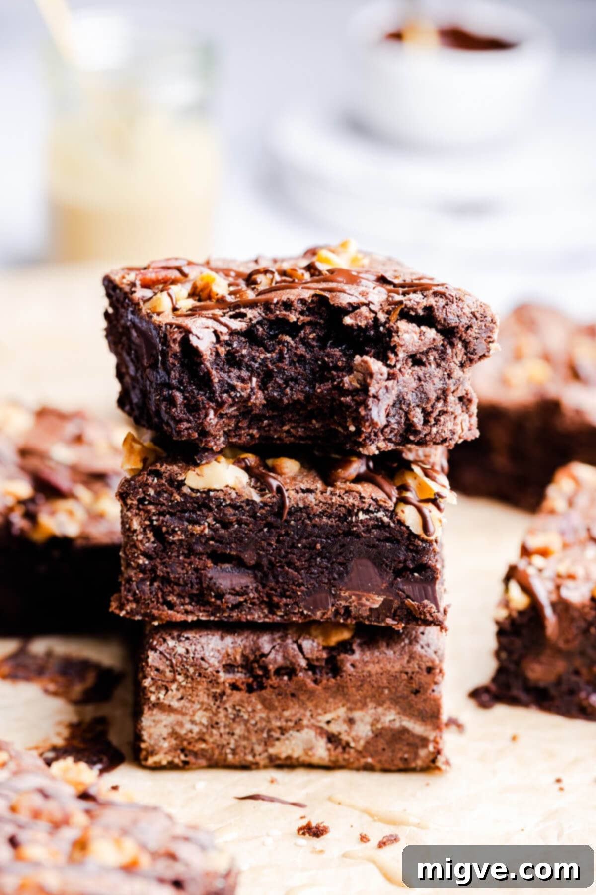 side view of three tahini brownies in a stack with the top one missing a bite, showing the rich fudgy interior and shiny top