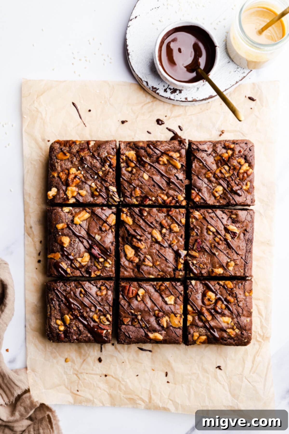 overhead view of 9 square slices of tahini and chocolate brownies with chocolate tahini drizzle and chopped walnuts