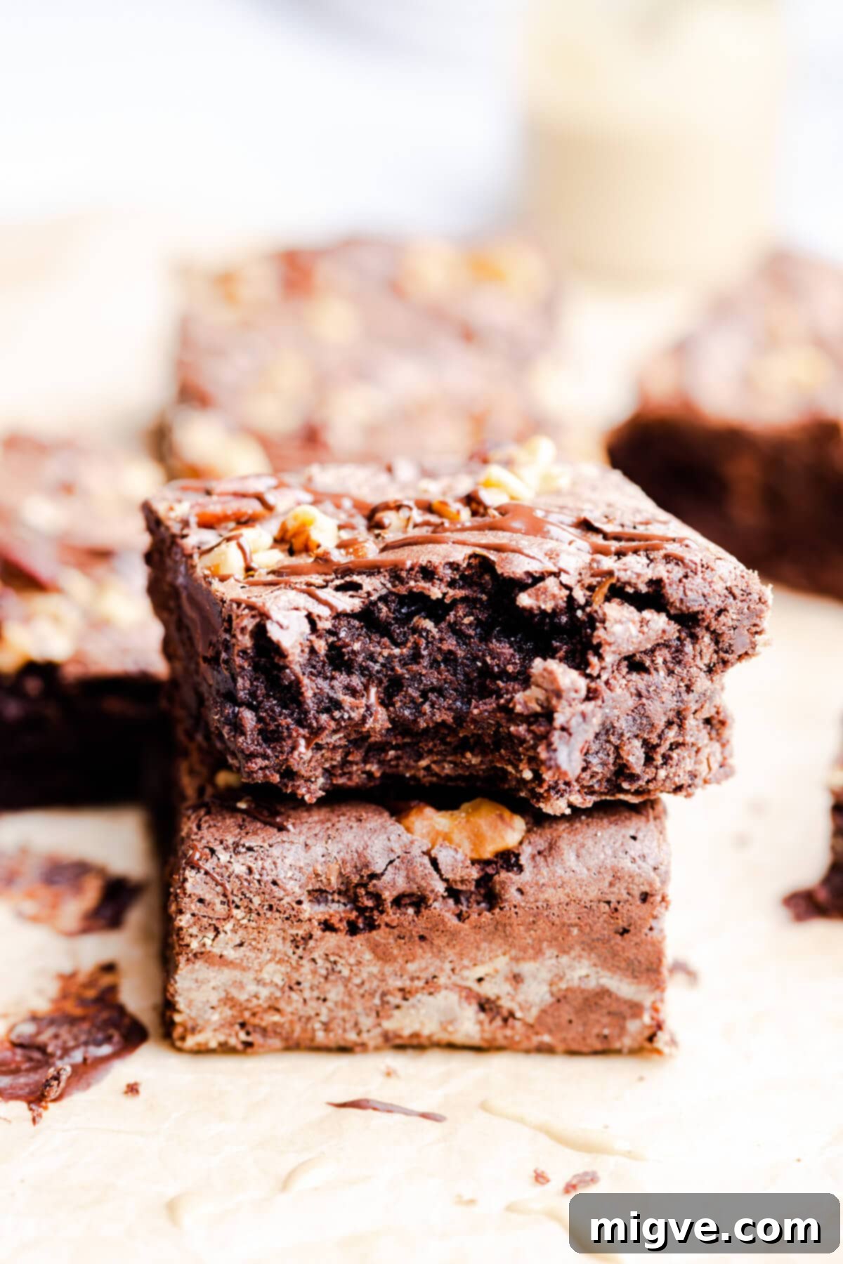 side close up of two chocolate tahini brownies with one missing a bite, showing the soft, rich texture