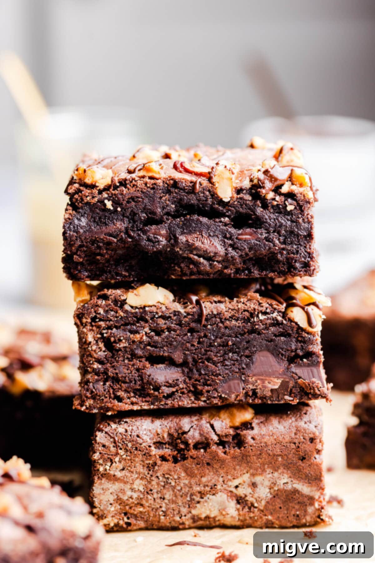side close up at a stack of three fudgy tahini brownies on top of each other, showing the thick, rich texture