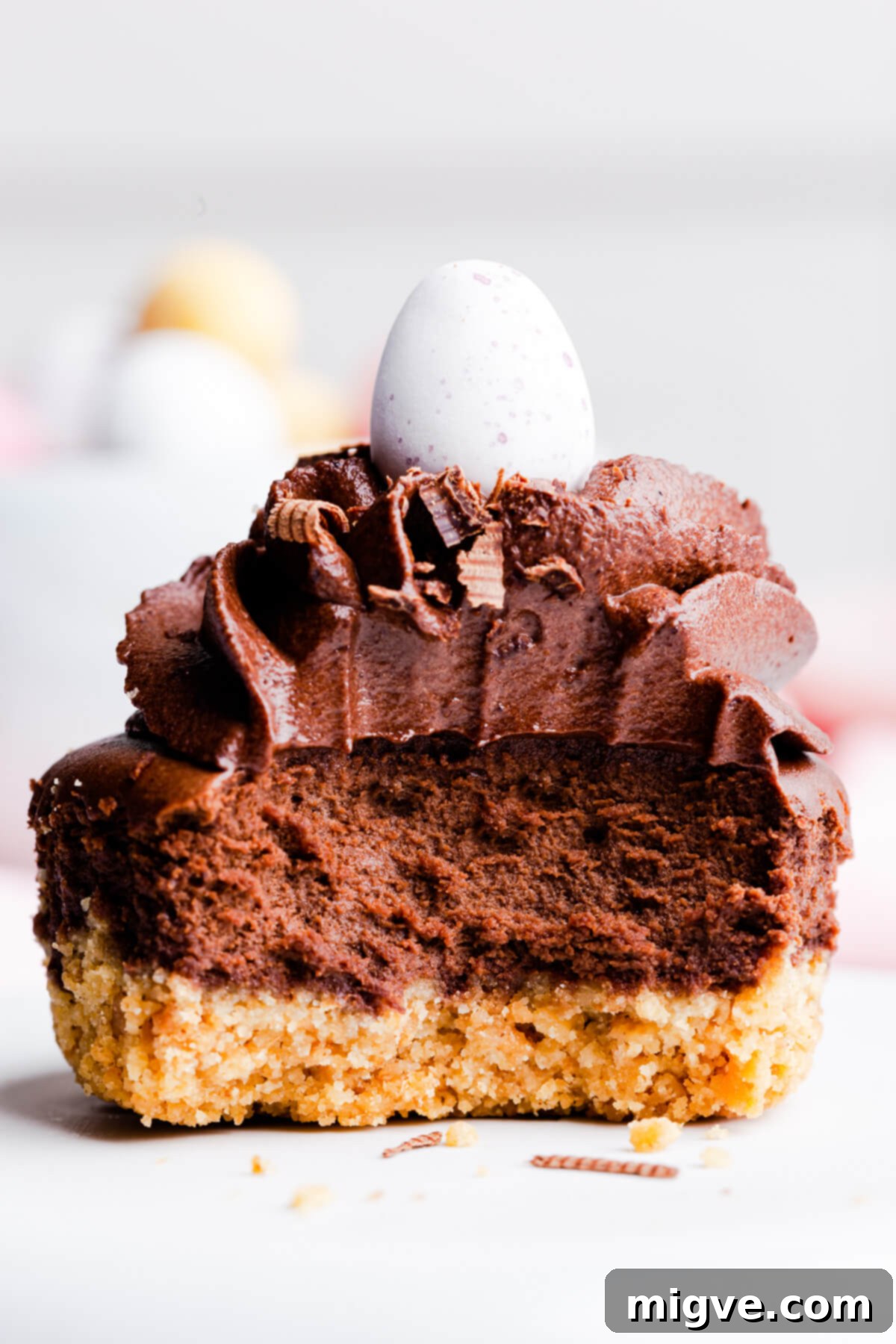 Super close-up, straight-ahead view of a mini chocolate cheesecake with a bite taken out, revealing its rich layers.