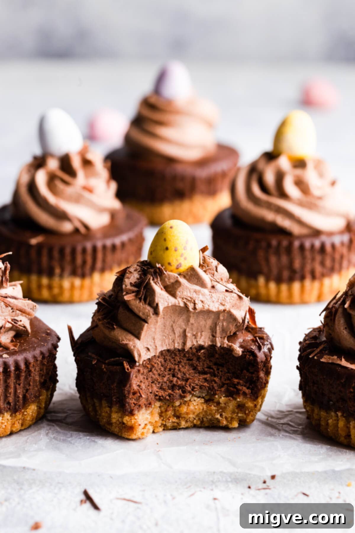 Close-up side view of a chocolate cheesecake with a bite taken out, resting on a rustic wooden surface.