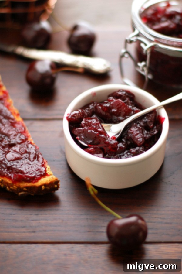 Another view of cherry jam with cinnamon in a jar, highlighting its texture and color.