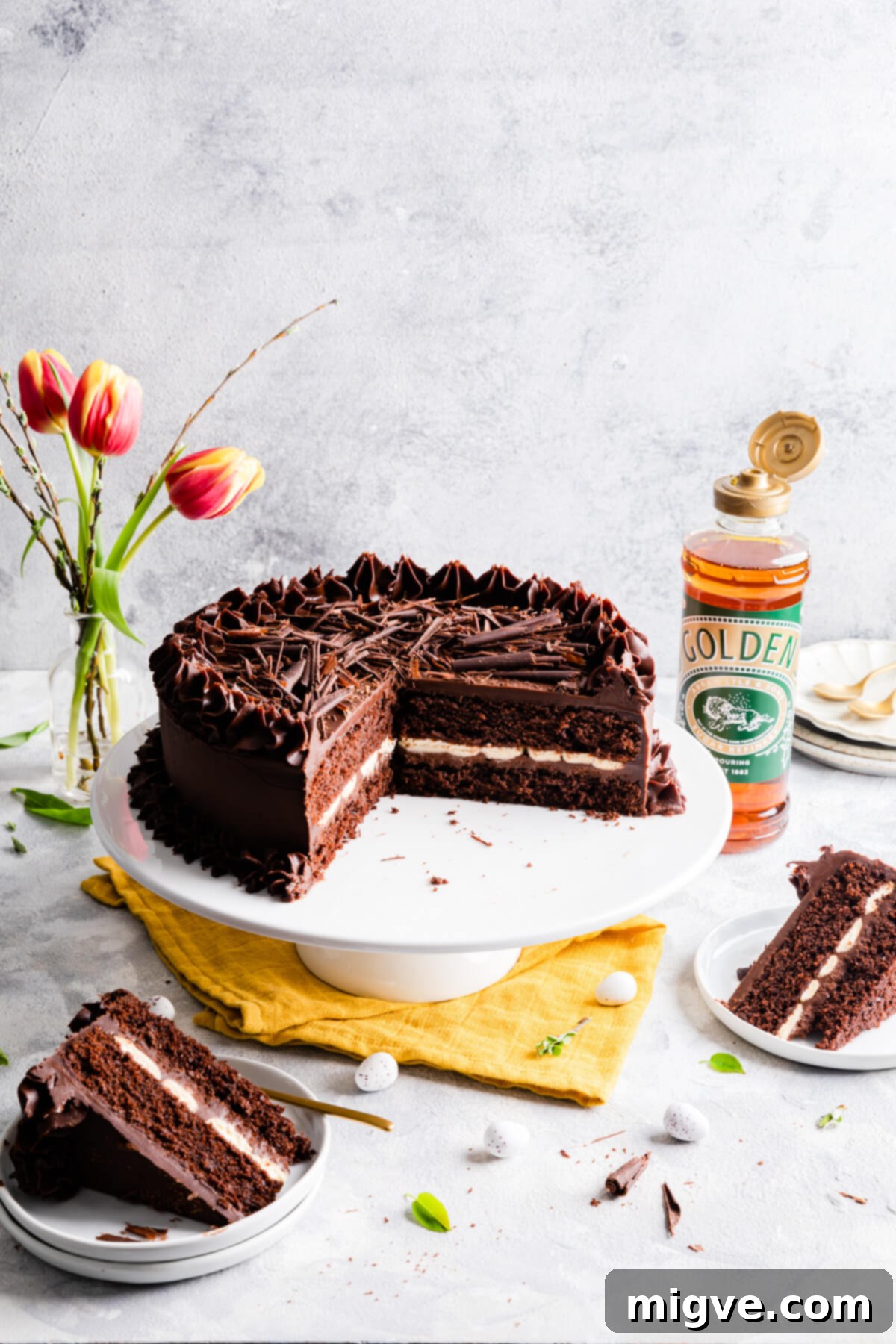 photo of a chocolate cake on a cake stand with few slices cut out