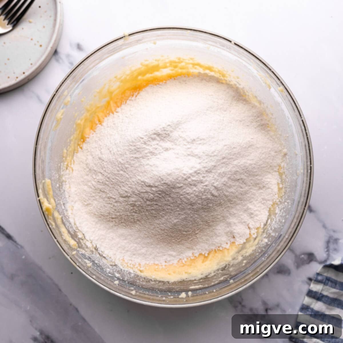 Classic Victoria Sponge 6 overhead view at a bowl with sifted flour and cake batter inside