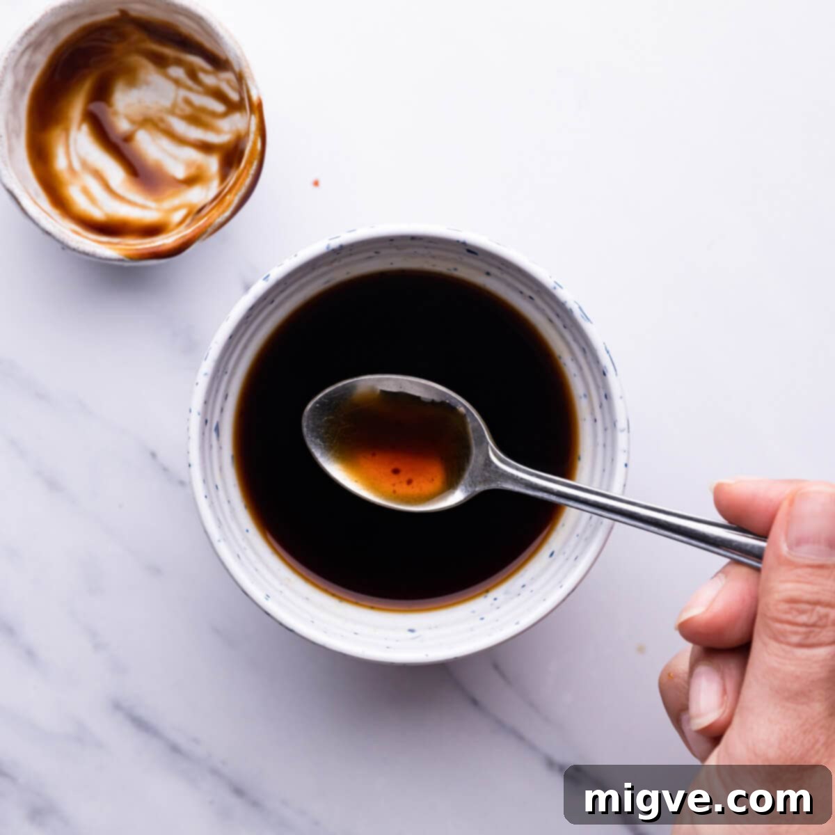 Crunchy Cashew Thai Chicken 4 top view of a person mixing the sauce with teaspoon