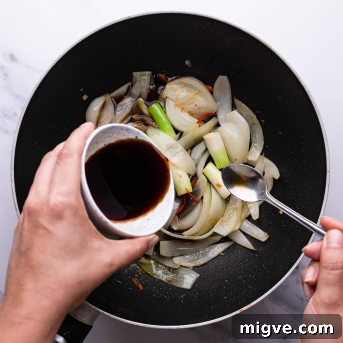 Crunchy Cashew Thai Chicken 8 overhead view of a person pouring sauce into vegetables