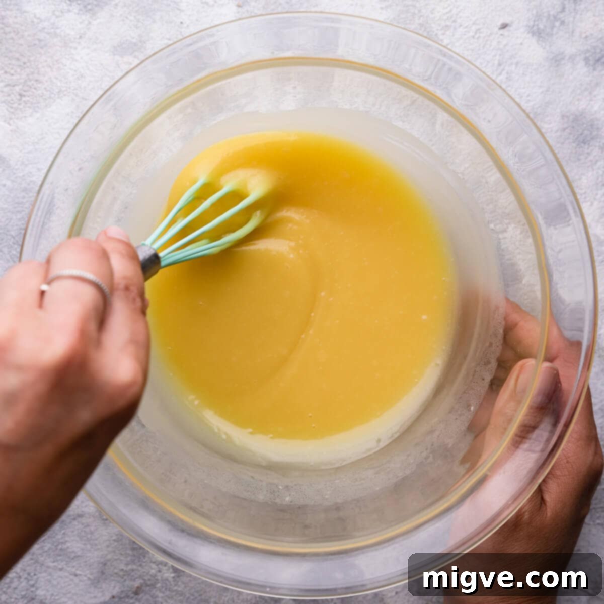 Top-down view of perfectly smooth and shiny white chocolate ganache in a bowl, having cooled and thickened slightly, ready for application.