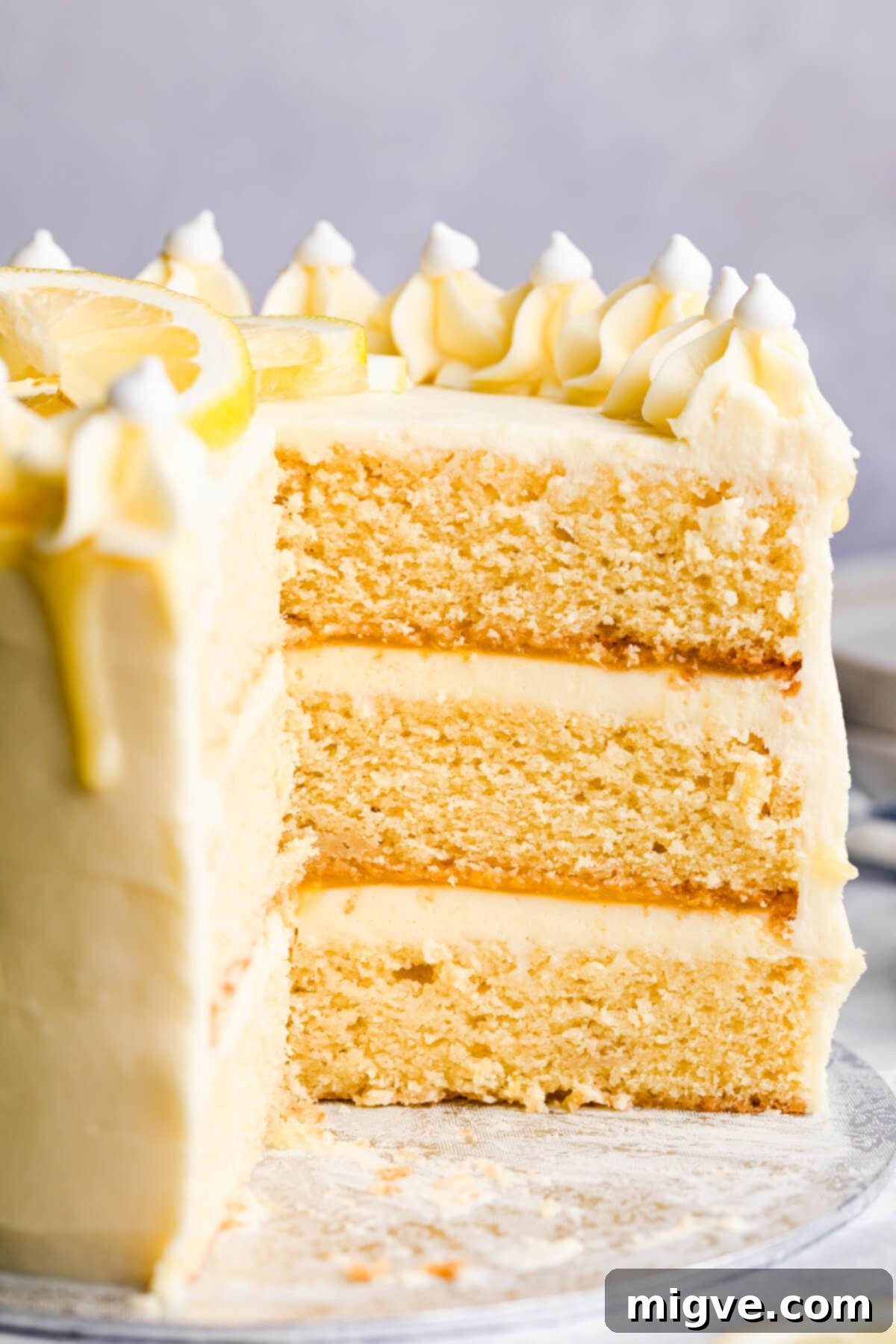 A stunning side close-up view of the Lemon and Elderflower Cake, clearly showcasing its beautiful, distinct layers of moist sponge, fluffy elderflower buttercream, and tangy lemon curd.