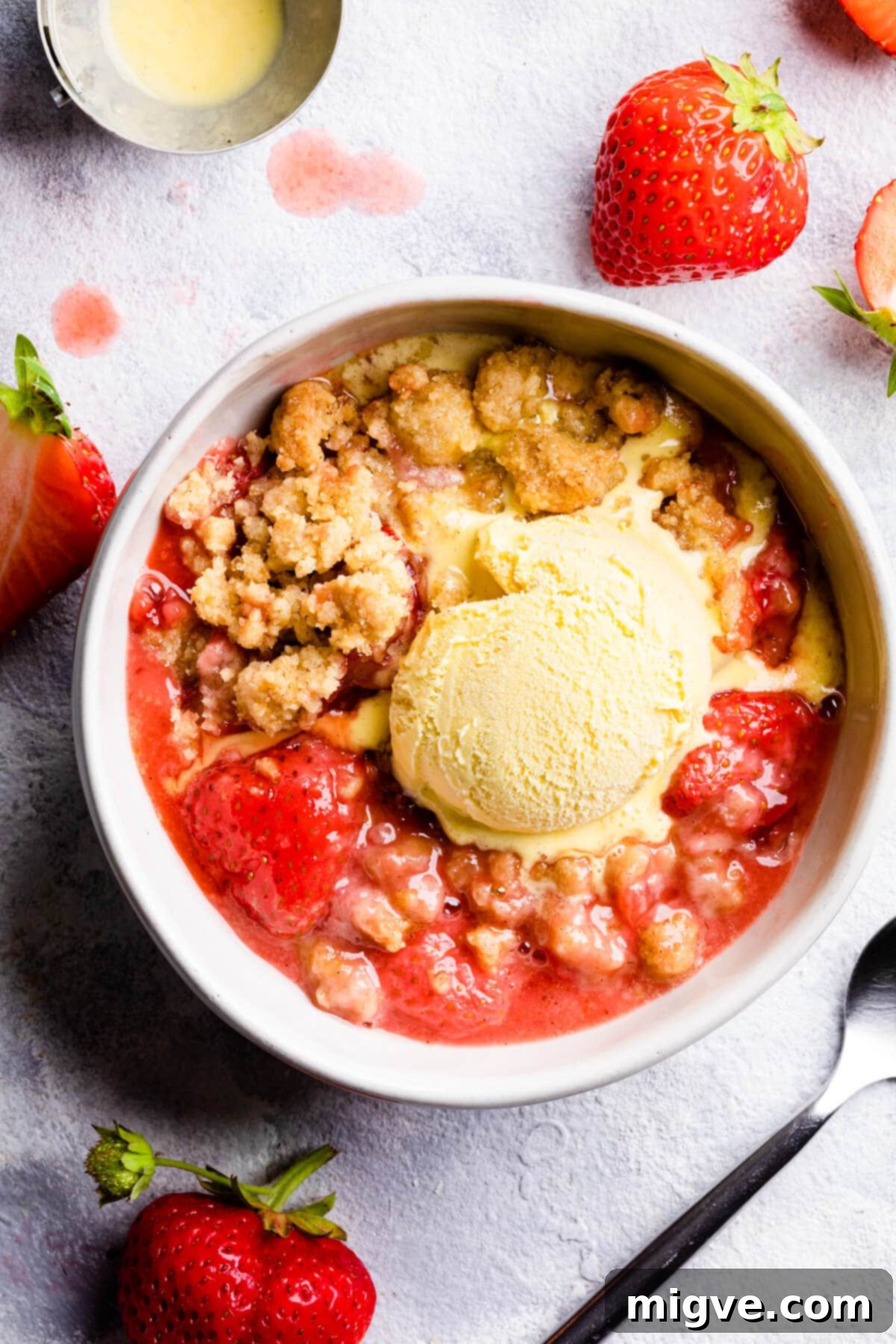 top down view of a bowl with strawberry crumble and a scoop of ice cream