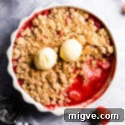strawberry crumble in a baking dish and two scoops of ice cream on top.