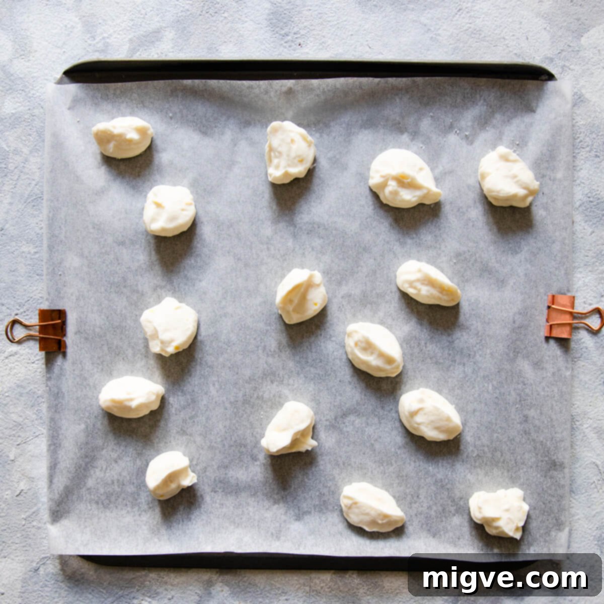 Shortcake Strawberry Cookies 4 Overhead view of small dollops of cream cheese mixture arranged on a baking sheet, ready for freezing.