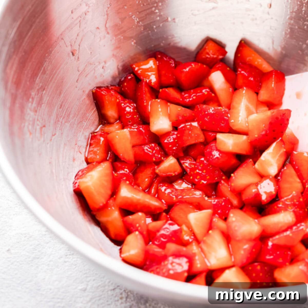 Shortcake Strawberry Cookies 5 Close-up side view of finely chopped fresh strawberries in a bowl, glistening with sugar and lemon juice.