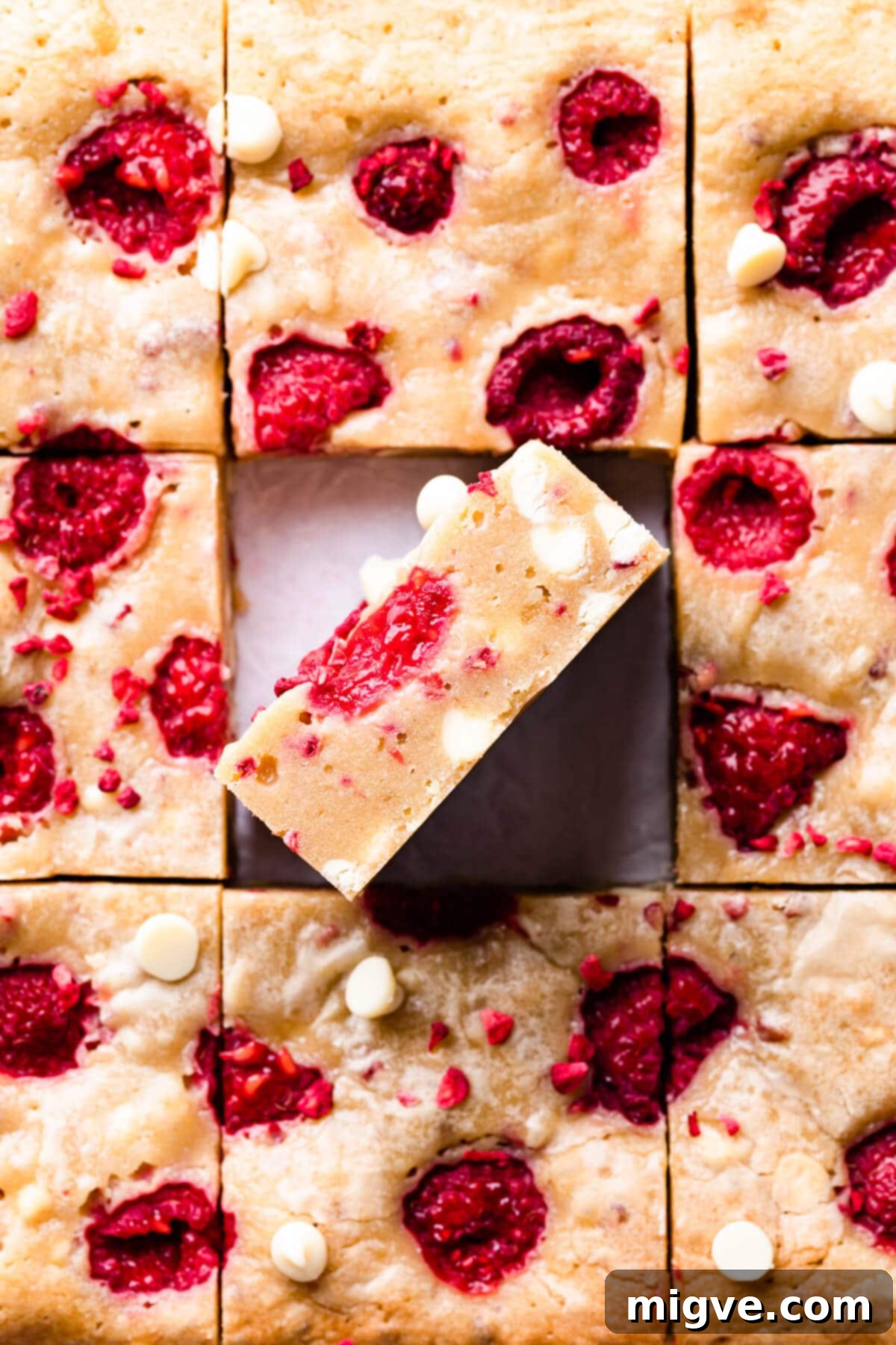 Square slices of fudgy white chocolate raspberry blondies, beautifully studded with fresh raspberries and white chocolate pieces.