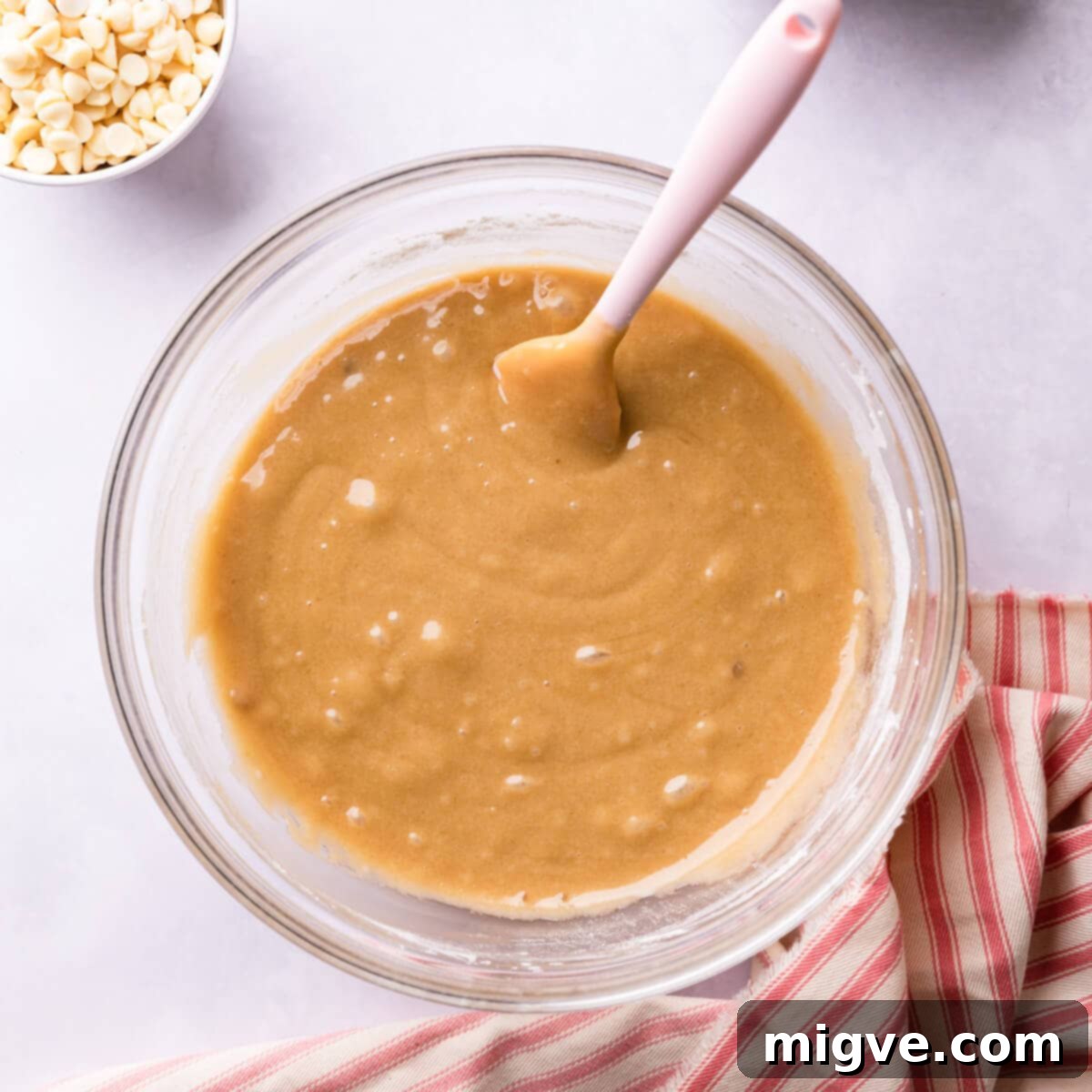 A bowl showing raw blondie batter, with a spatula used to fold in ingredients.