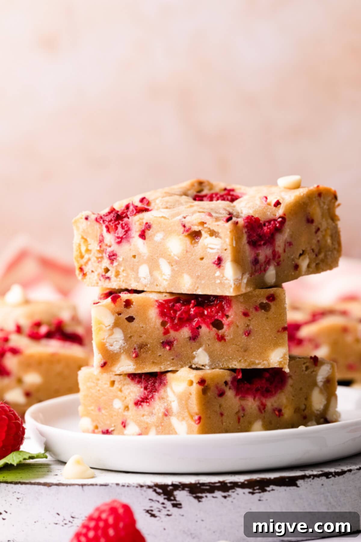 A charming stack of blondie bars adorned with white chocolate, presented on a small white plate.