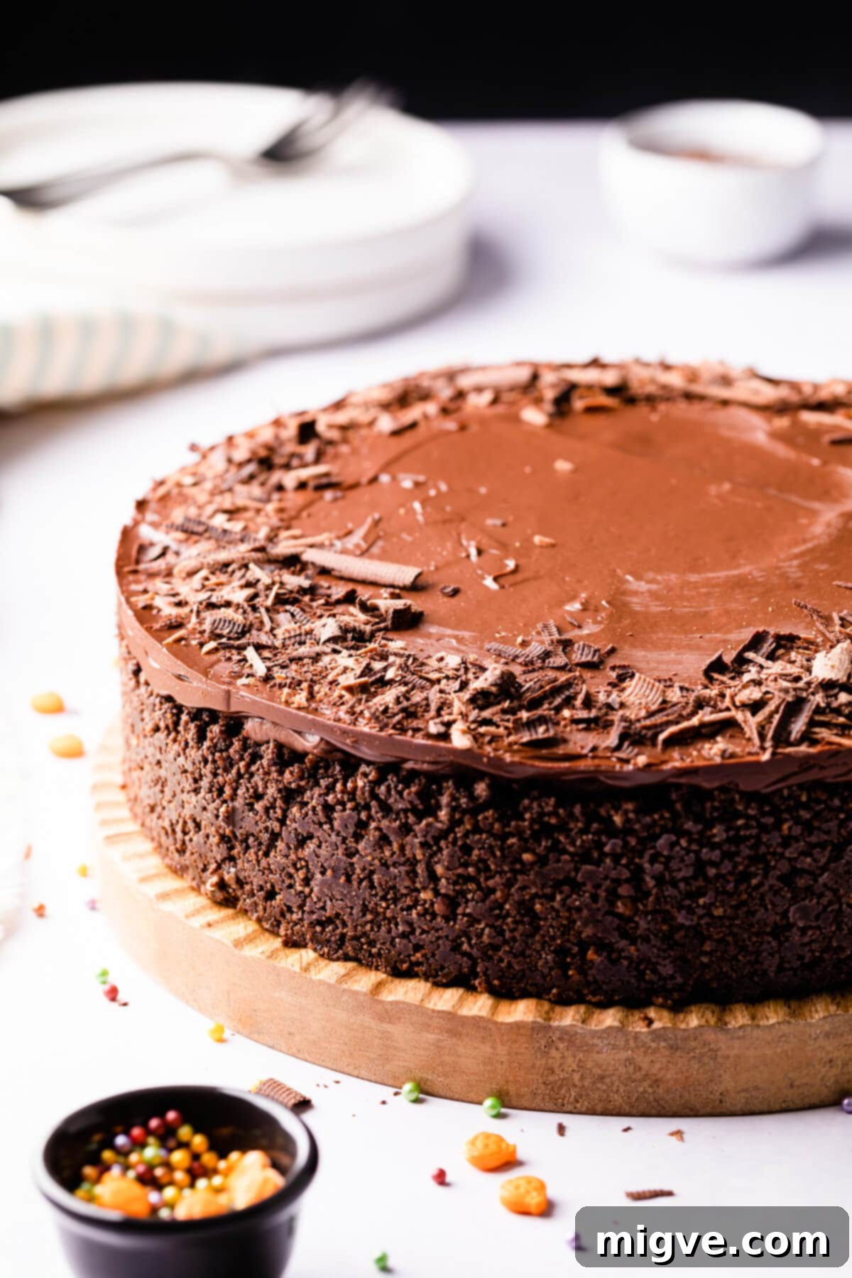 Sinfully Decadent Cheesecake 9 devil's food cheesecake on a wooden cake board and some sprinkles around it.