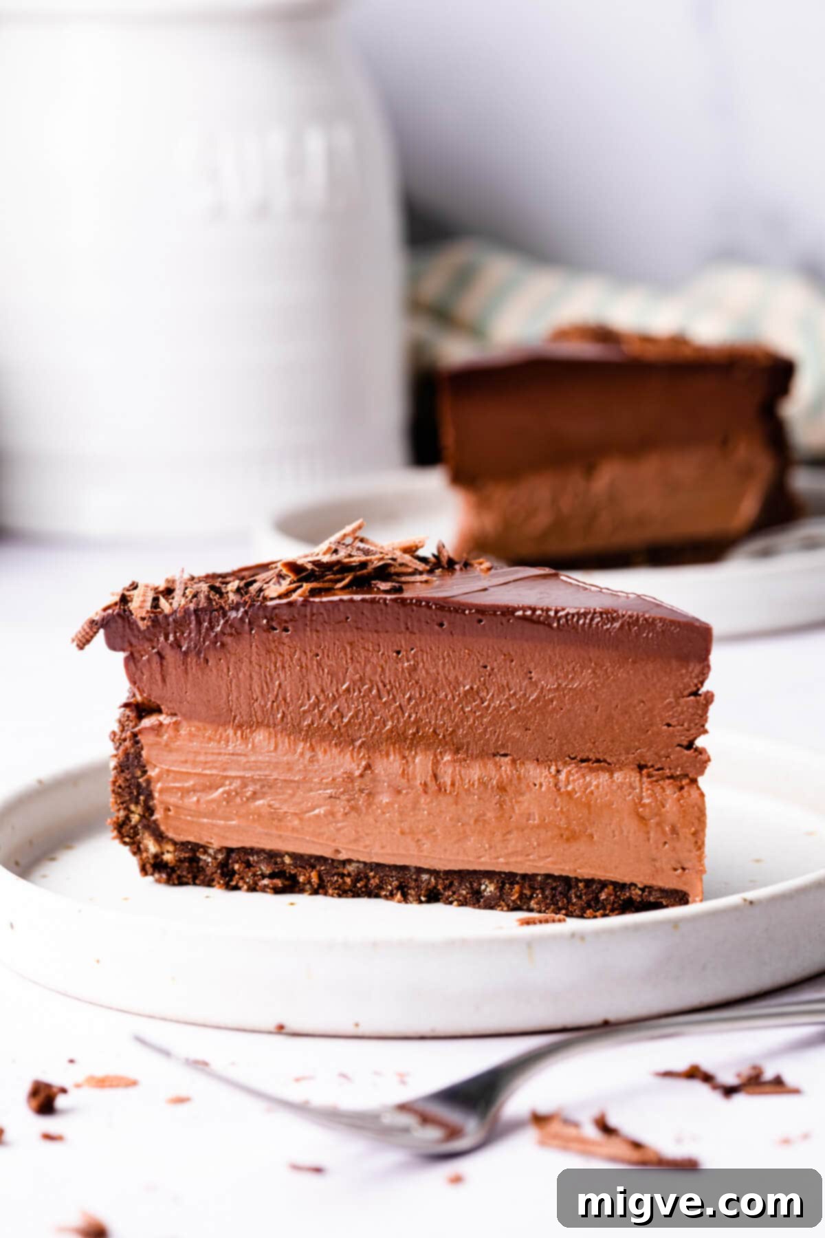 Sinfully Decadent Cheesecake 10 a single slice of triple chocolate cheesecake on a dessert plate and another slice behind it.