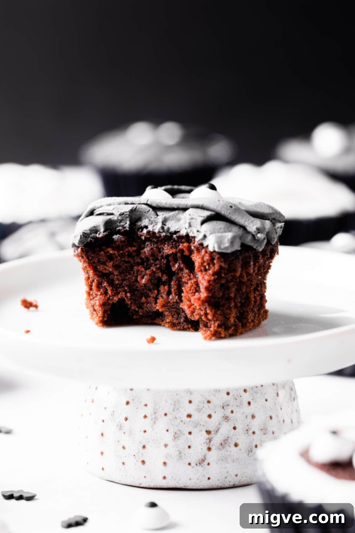 Bandaged Boo Cupcakes 12 An individual Halloween mummy cupcake resting on a small cake stand, with a bite taken out, revealing the moist chocolate interior.