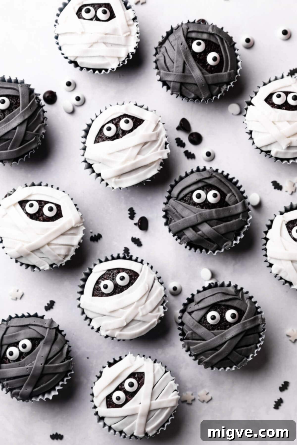 Bandaged Boo Cupcakes 13 A trio of perfectly decorated chocolate cupcakes, two with white icing and one with black, all featuring prominent sugar eyes, showcasing the mummy theme.