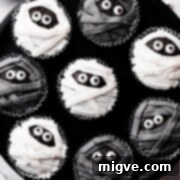 Bandaged Boo Cupcakes 14 chocolate cupcakes decorated with black and white icing and sugar eyes on a black background.