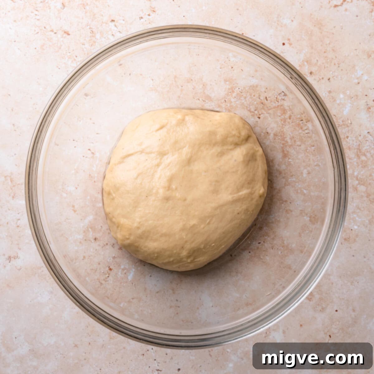 Freshly kneaded yeasted dough resting in a glass bowl, ready for its first rise.