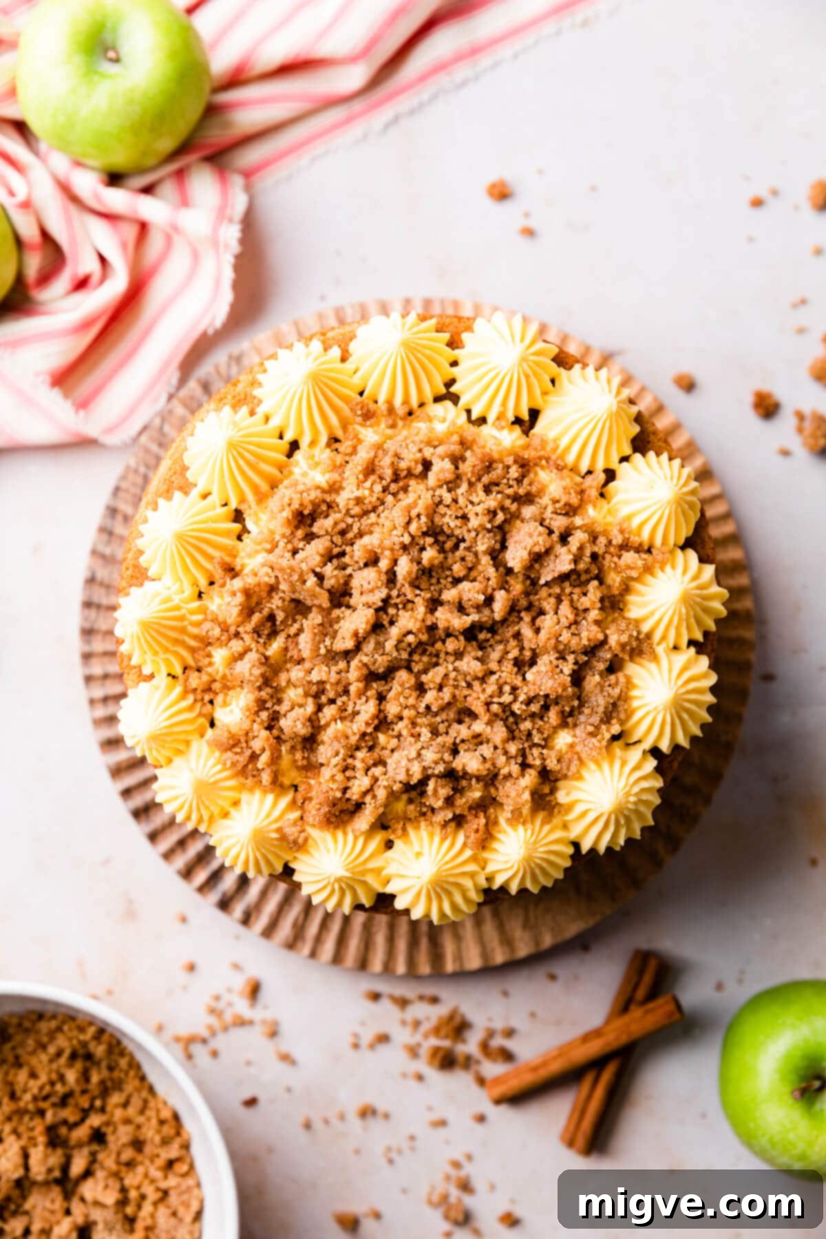 an apple crumble cake with piped buttercream and crumble topping.