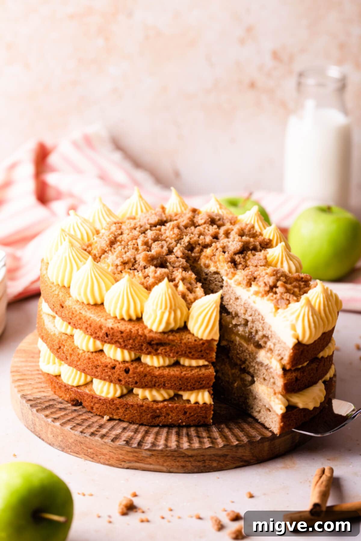 apple cake on a wooden cake stand with a slice being cut out.