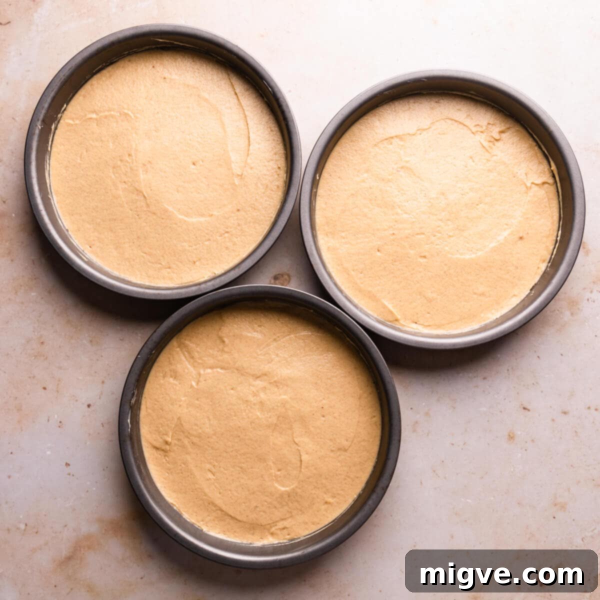 3 round baking tins filled with batter for apple crumble cake.