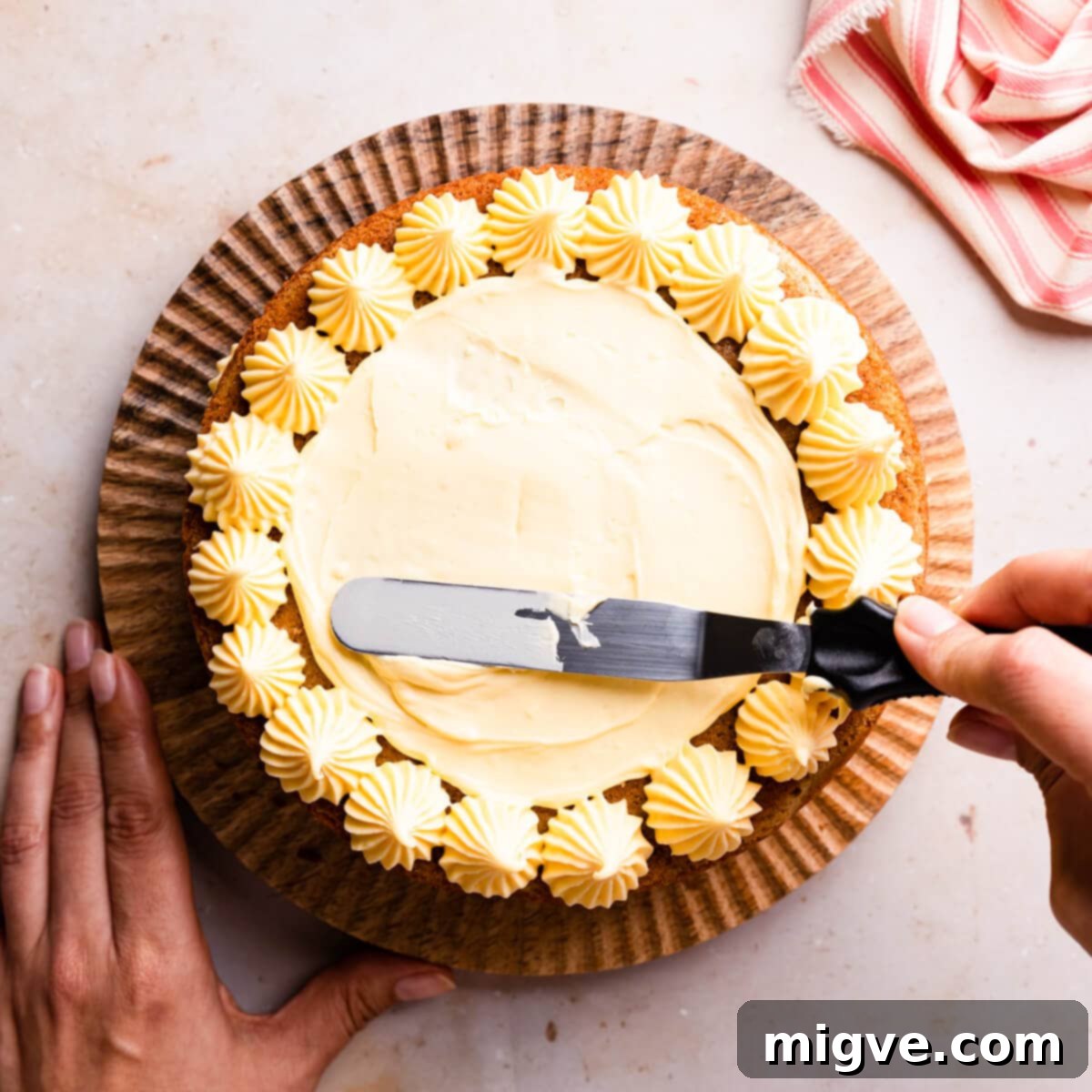 custard buttercream being spread with an offset spatula on top of the sponge cake.