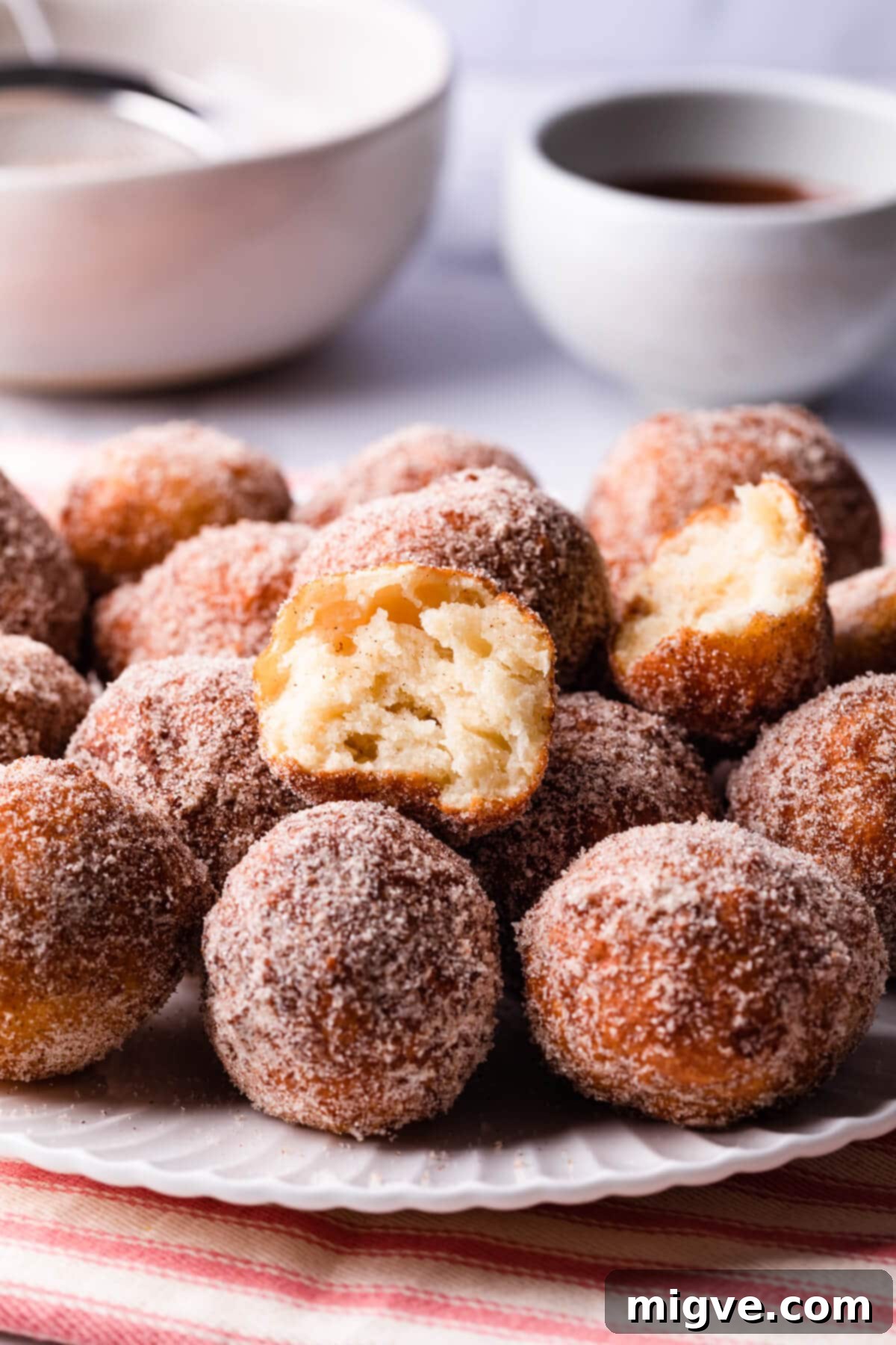 tofu donuts on a white plate coated in cinnamon sugar.