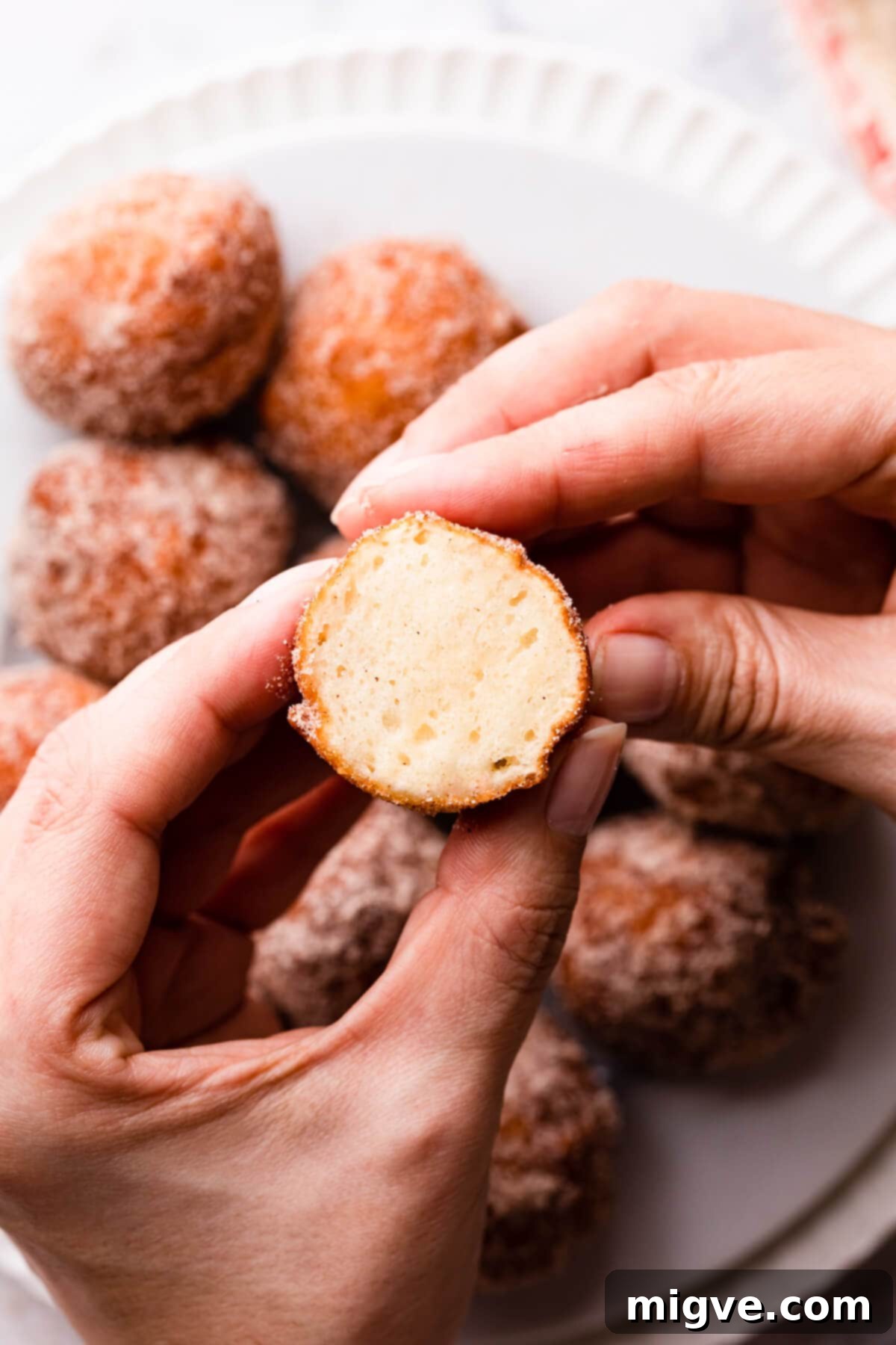 half of mini donut made with tofu being held in hands.