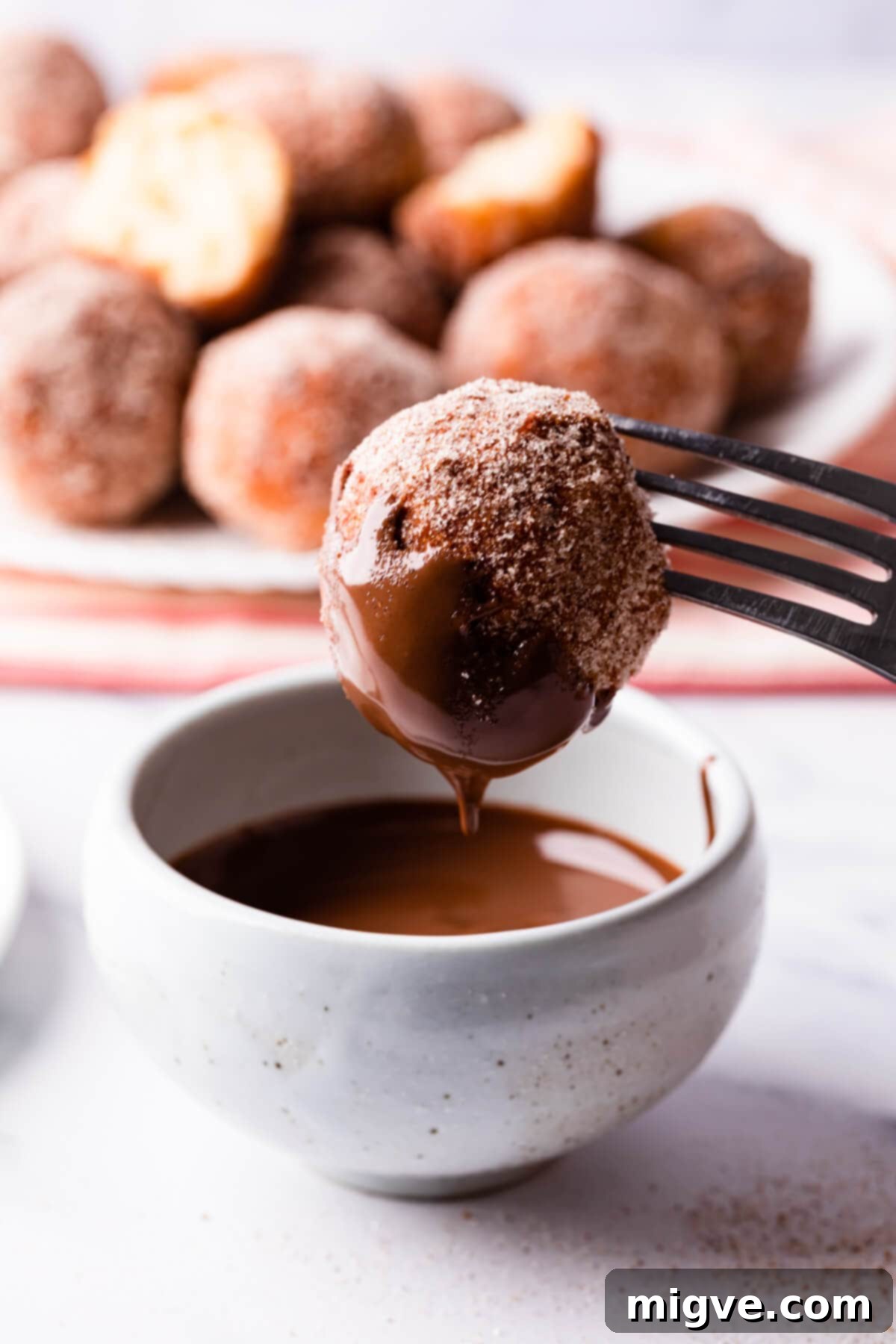 tofu doughnut being dipped in melted chocolate.