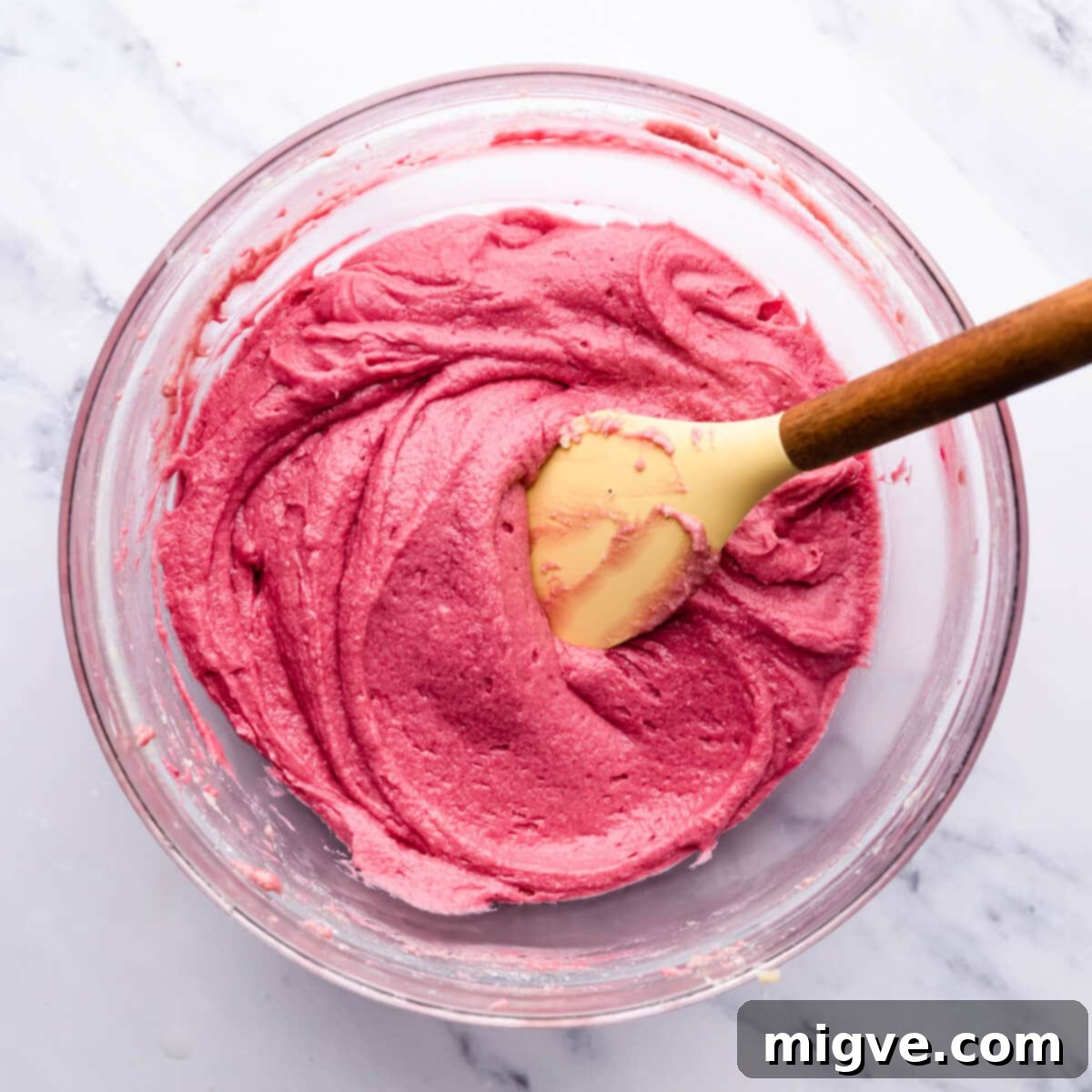 Decadent Raspberry Chocolate Cupcakes 5 glass bowl with pink cupcake batter and spatula inside, showing smooth consistency.