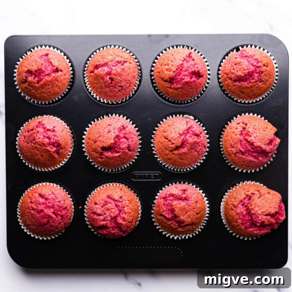 Decadent Raspberry Chocolate Cupcakes 7 baked raspberry cupcakes inside of the baking tin, golden brown and risen.