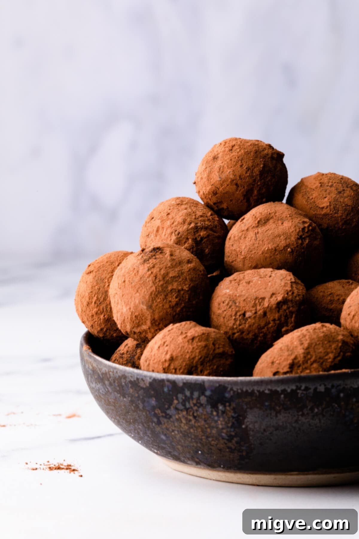 small bowl with a pile of salted caramel truffles dusted in cocoa powder.