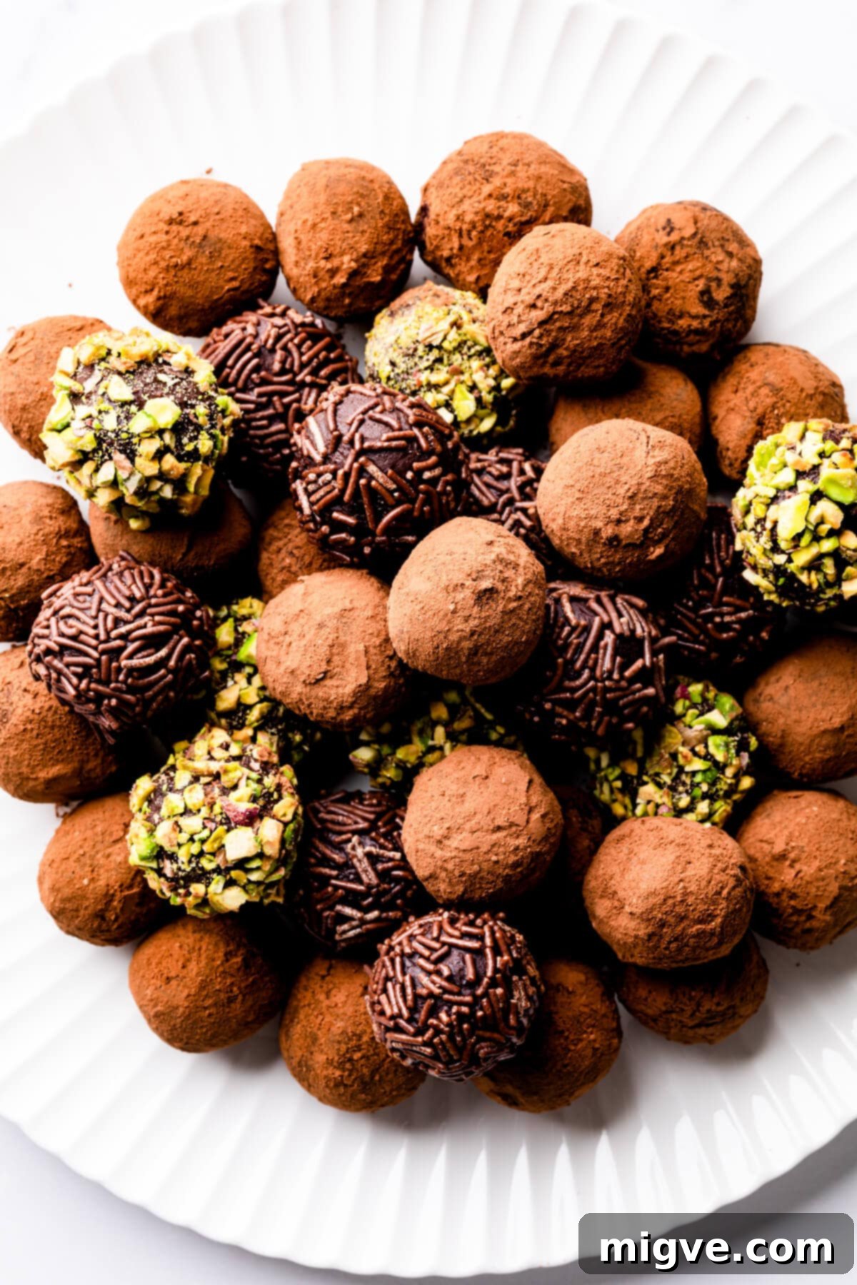 a pile of chocolate truffles on a white plate.