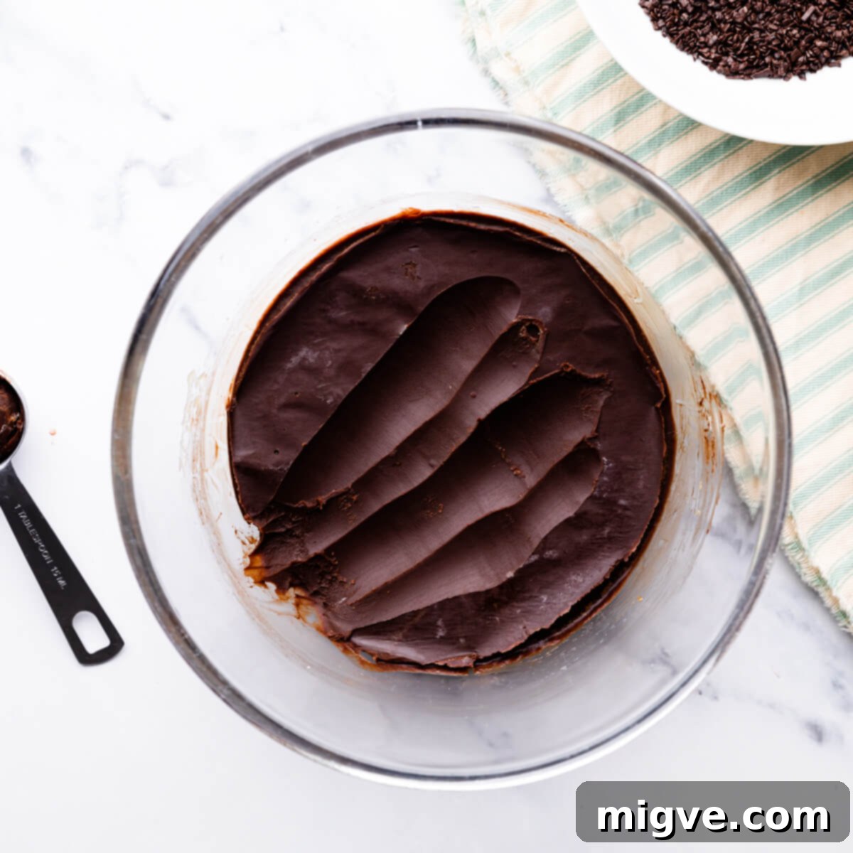 bowl with set and firm chocolate ganache and some of it scooped out.