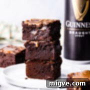 stack of 3 chocolate Guinness brownies on a white plate with can of Guinness in a background.