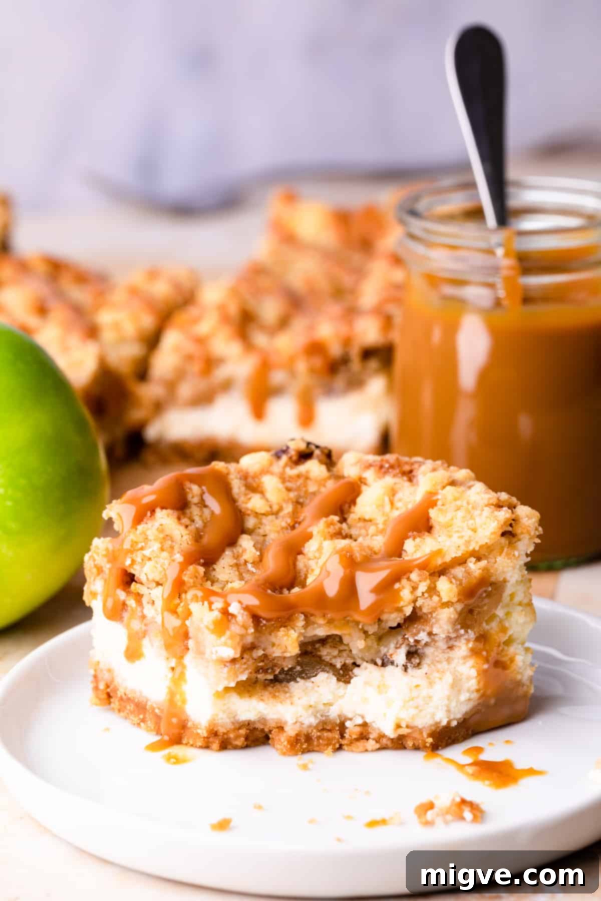 A charming and inviting flat lay image showcasing a single, perfectly sliced caramel apple cheesecake bar on a small white plate next to a cup of coffee, accompanied by fresh apples and cinnamon sticks, evoking a cozy autumn vibe.