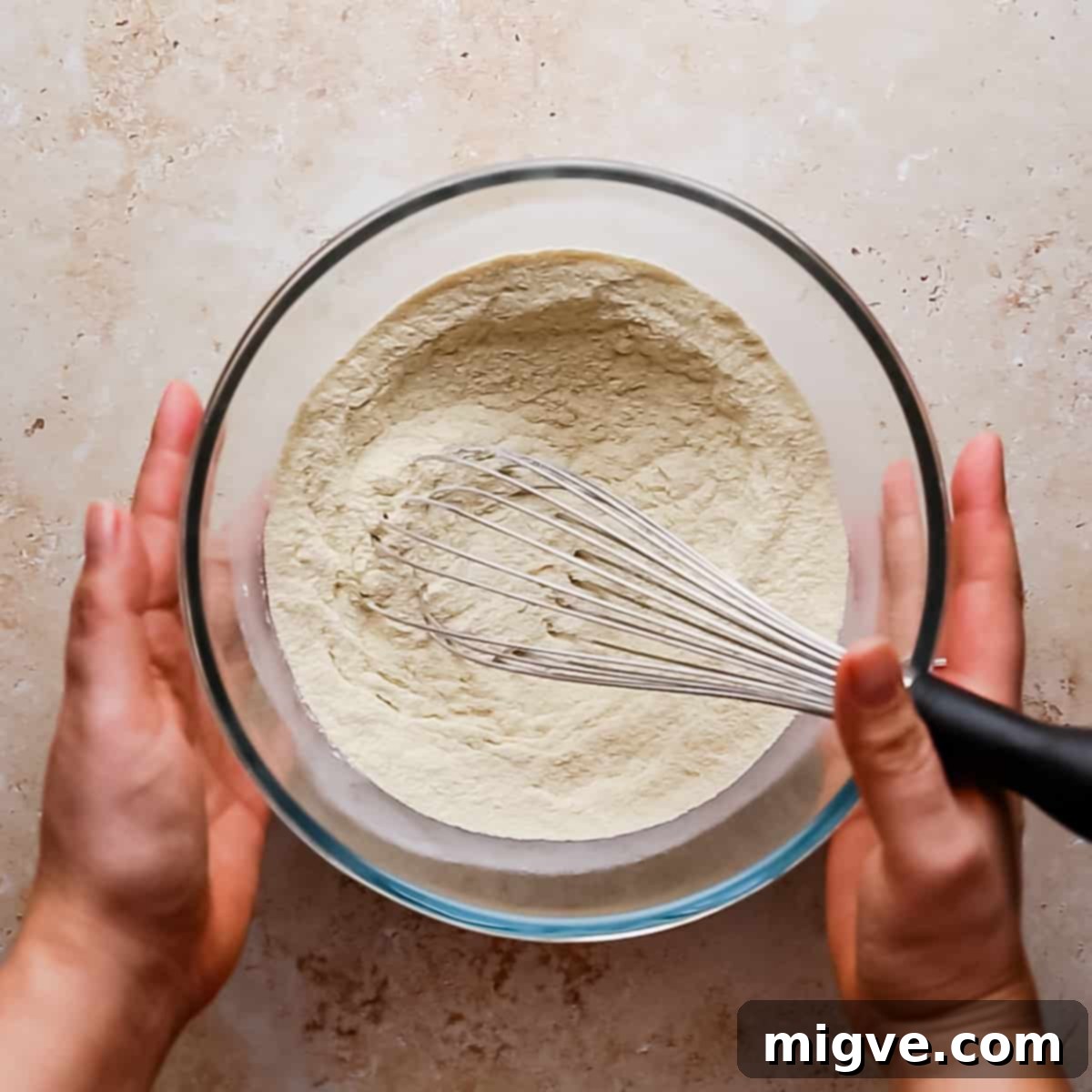 mixing bowl with dry ingredients being combined with kitchen whisk.