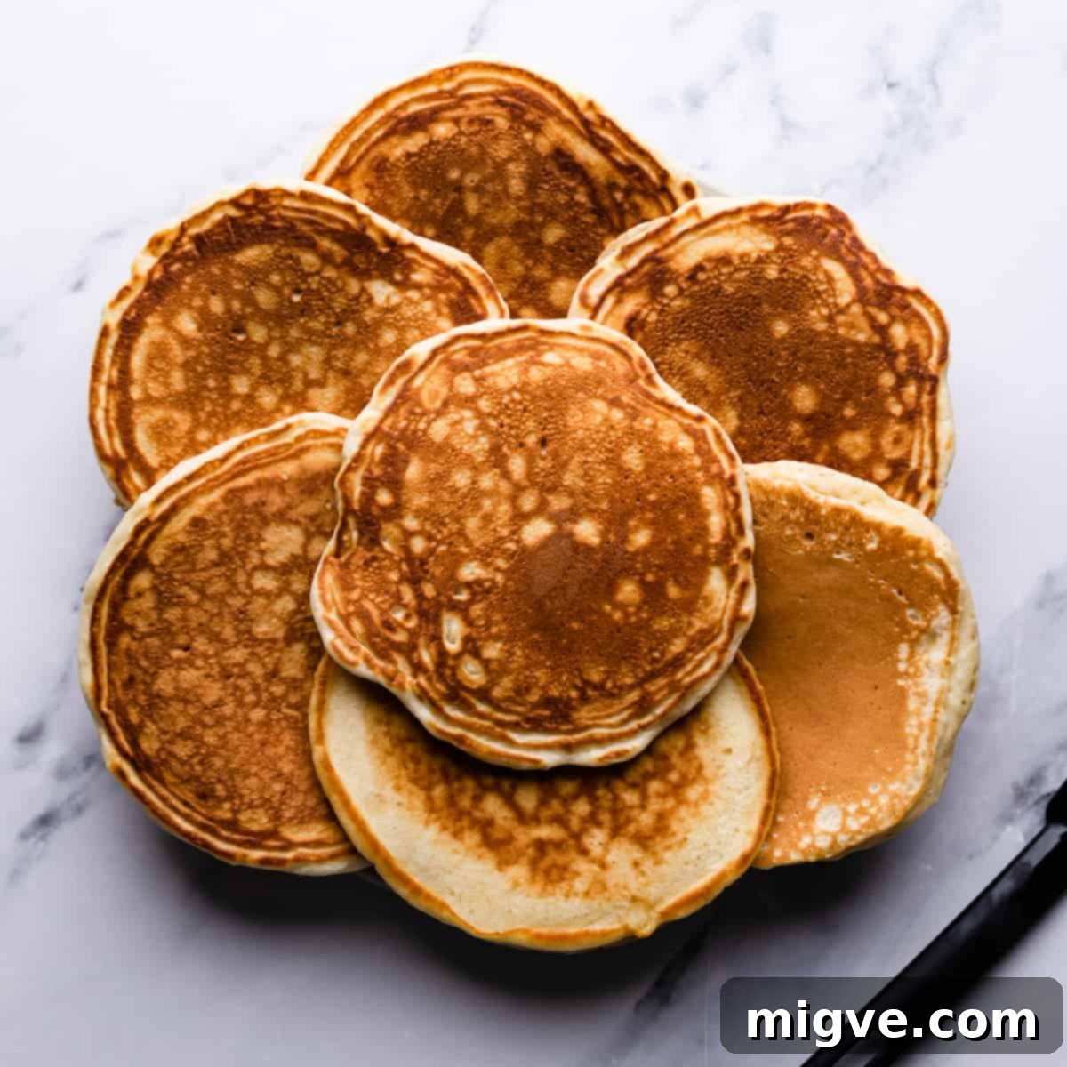 Baked Blueberry Pancake Bliss 5 Seven golden brown fluffy pancakes arranged neatly next to a small black spatula.
