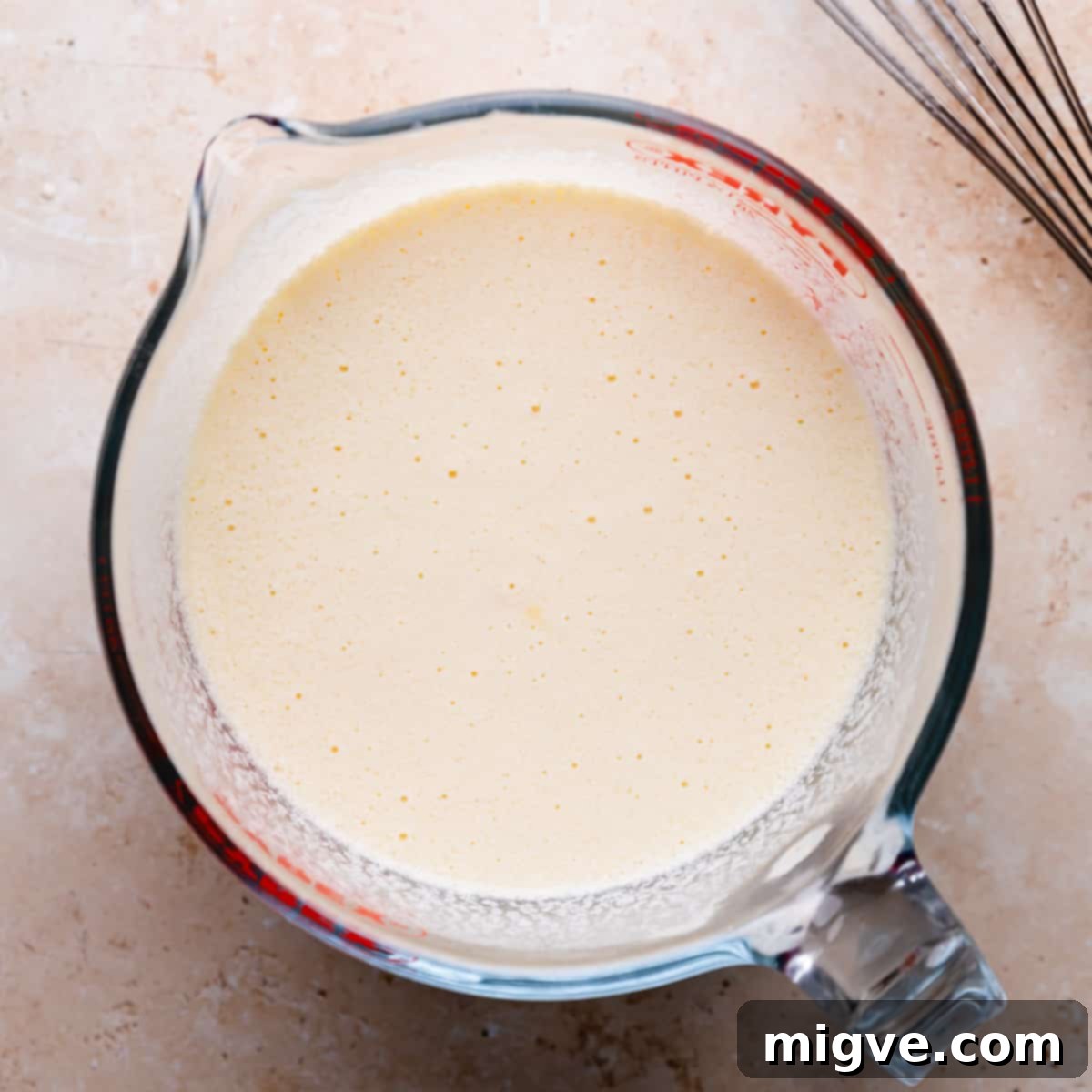 A large glass jug containing all the wet ingredients for muffins, whisked until well combined.