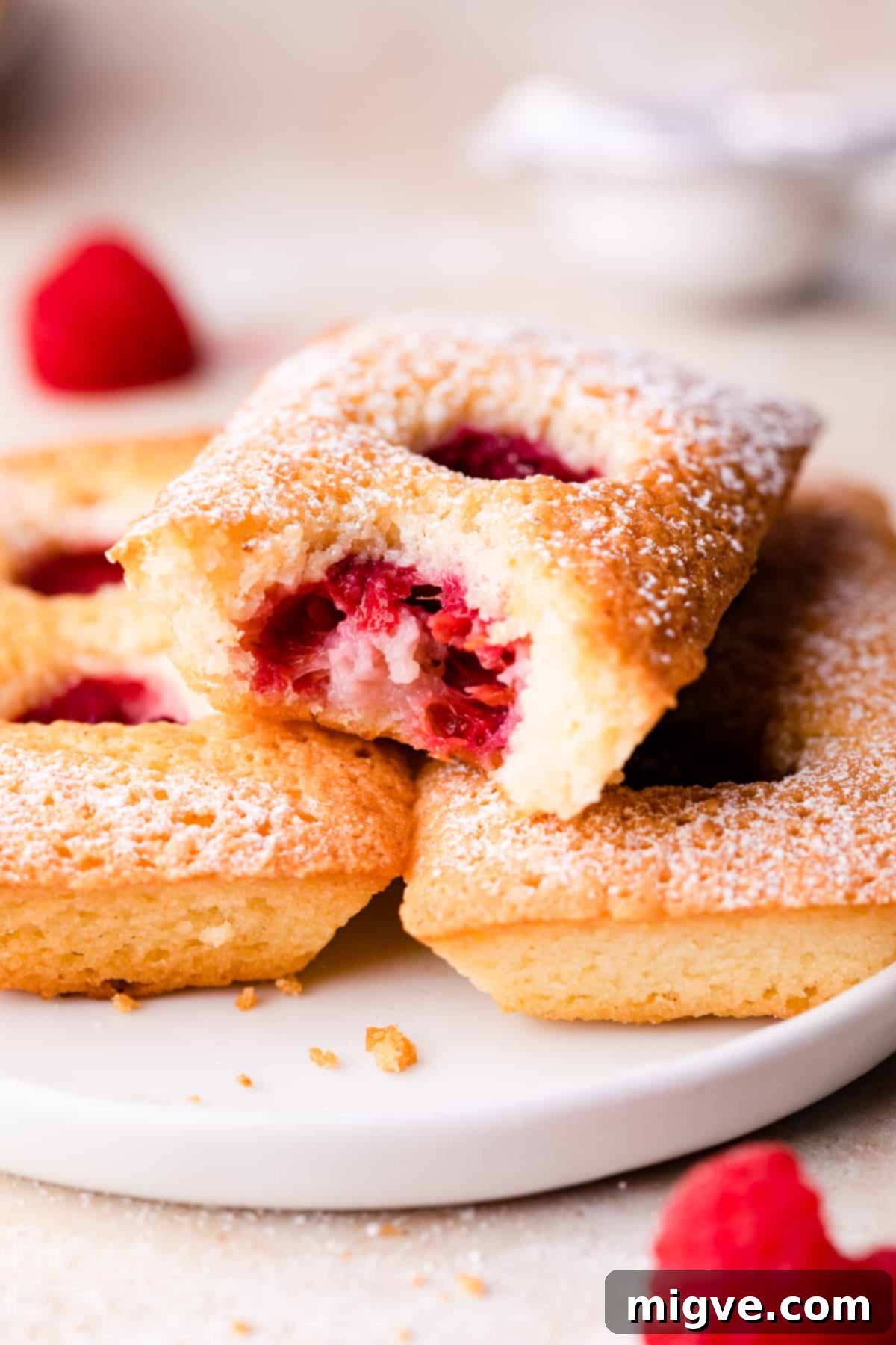 raspberry almond financier cake with bite taken out of it and raspberry in the middle.