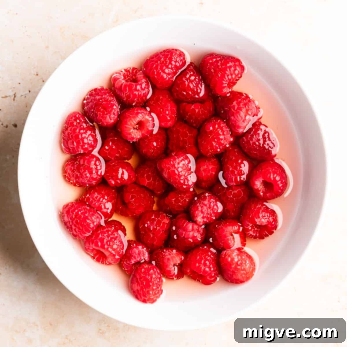 white ceramic bowl with raspberries soaked in rose wine.