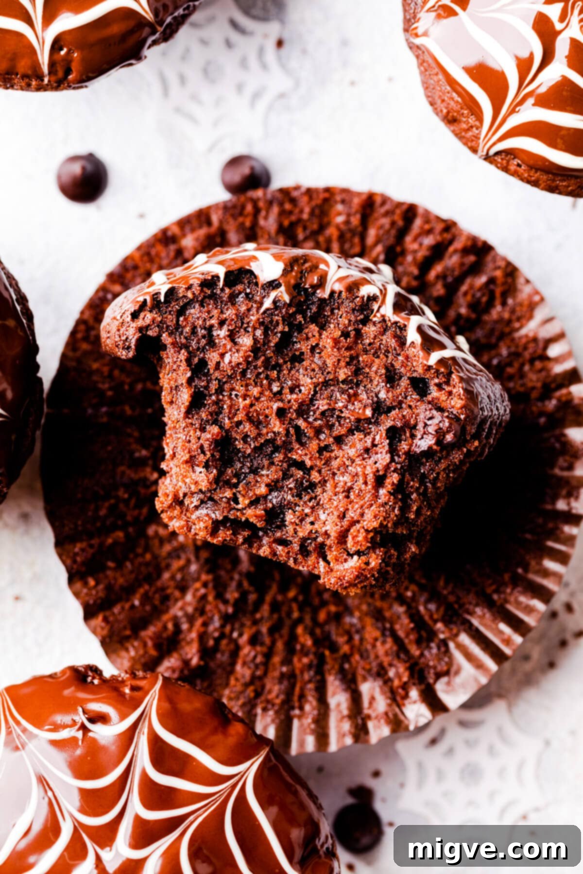 An individual chocolate fudge muffin with a bite taken out, revealing its moist and tender interior.