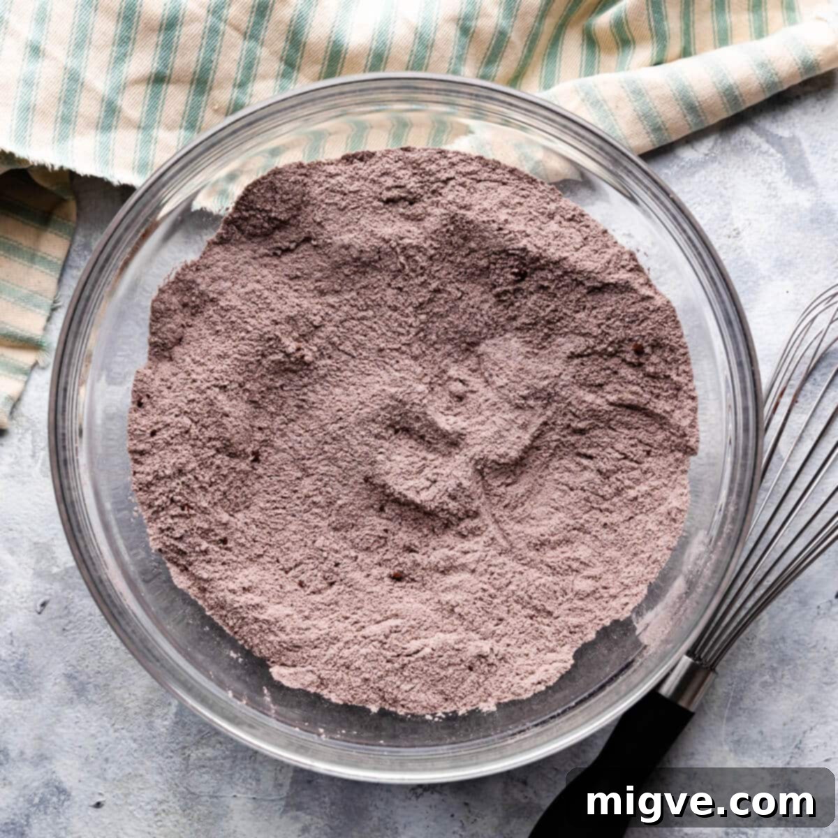 A large mixing bowl filled with dry ingredients for chocolate muffins, ready for the wet ingredients to be added.
